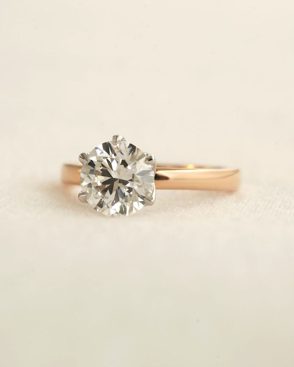 Close up shot of 2ct round brilliant engagement ring in rose gold with white gold prongs.