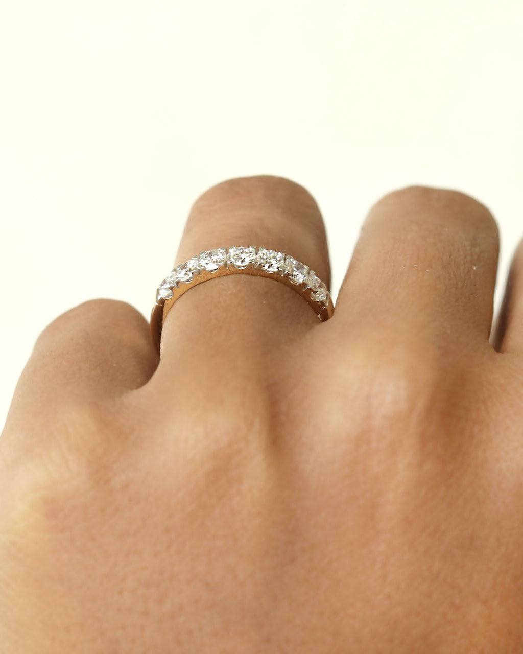 Hand wearing a 7 stone half eternity diamond ring .