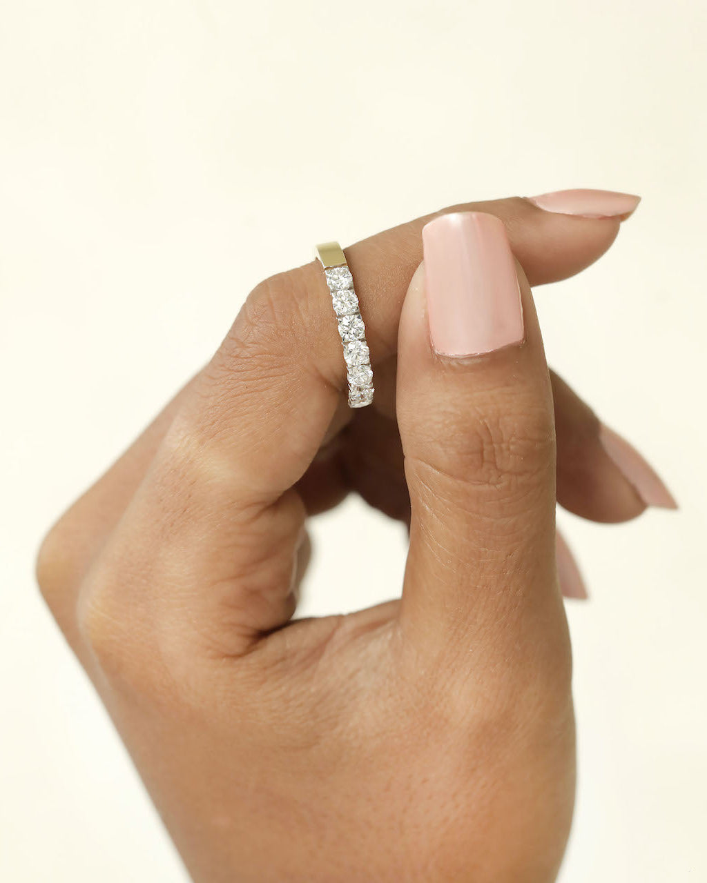 Hand holding a 7 stone half eternity diamond ring.