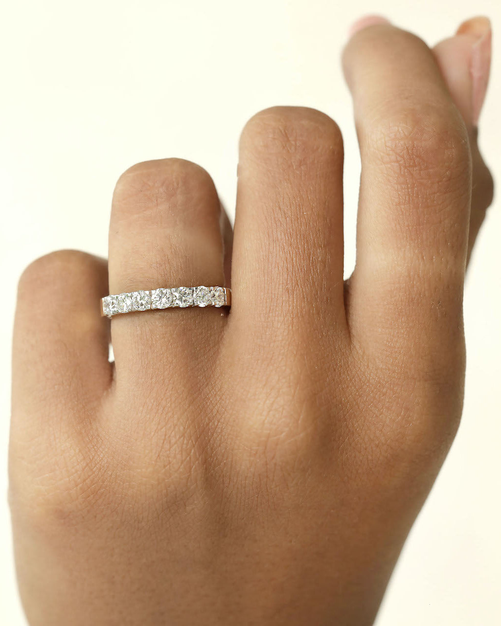 A hand wearing a 7 stone half eternity diamond ring.