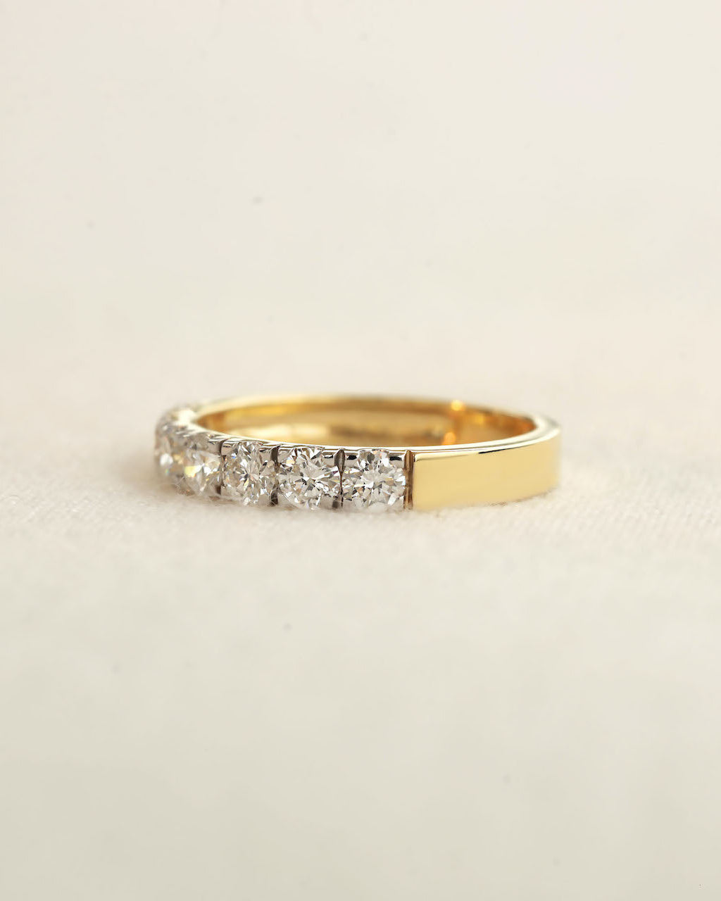 A yellow gold 7 stone half eternity diamond ring on white background.
