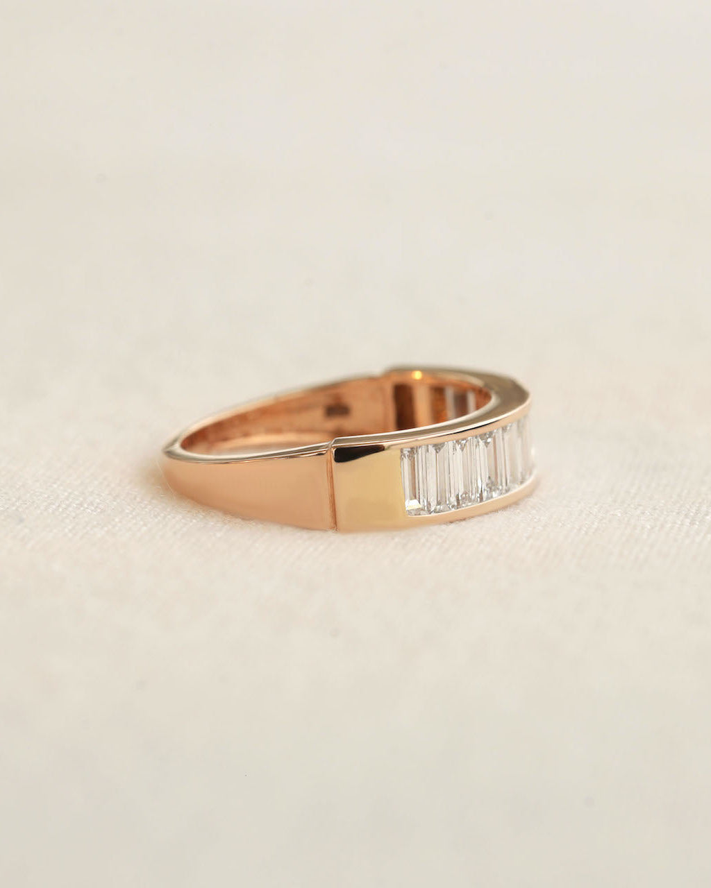 Side view of baguette cut lab diamond eternity ring in rose gold on white background.
