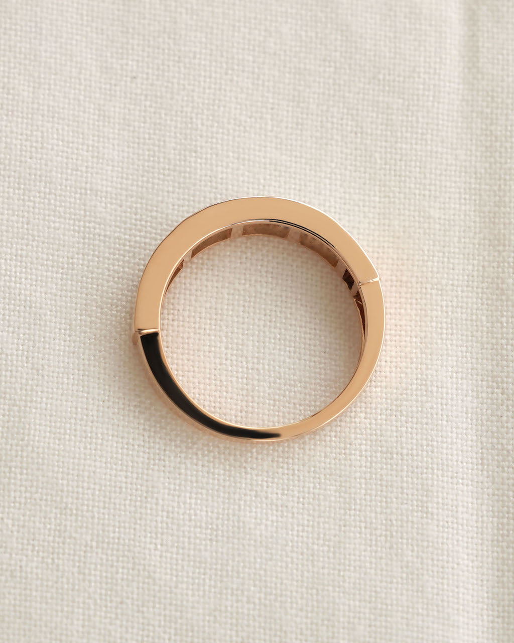 Close up shot of baguette cut lab diamond eternity ring in rose gold on white background.