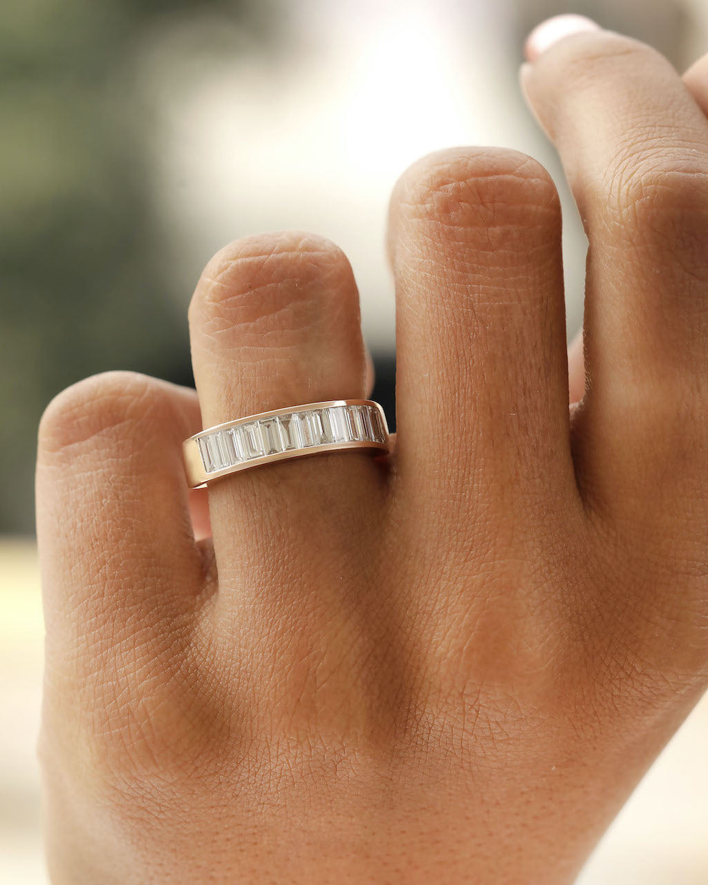 Hand wearing baguette Cut Lab diamond eternity ring in rose gold.