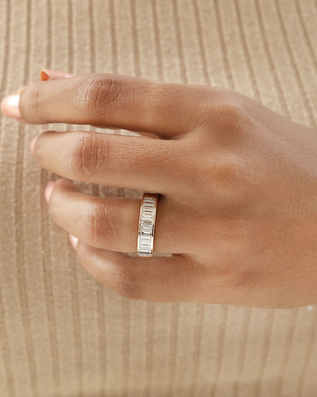 Hand wearing baquette Cut Lab diamond eternity ring in rose gold.