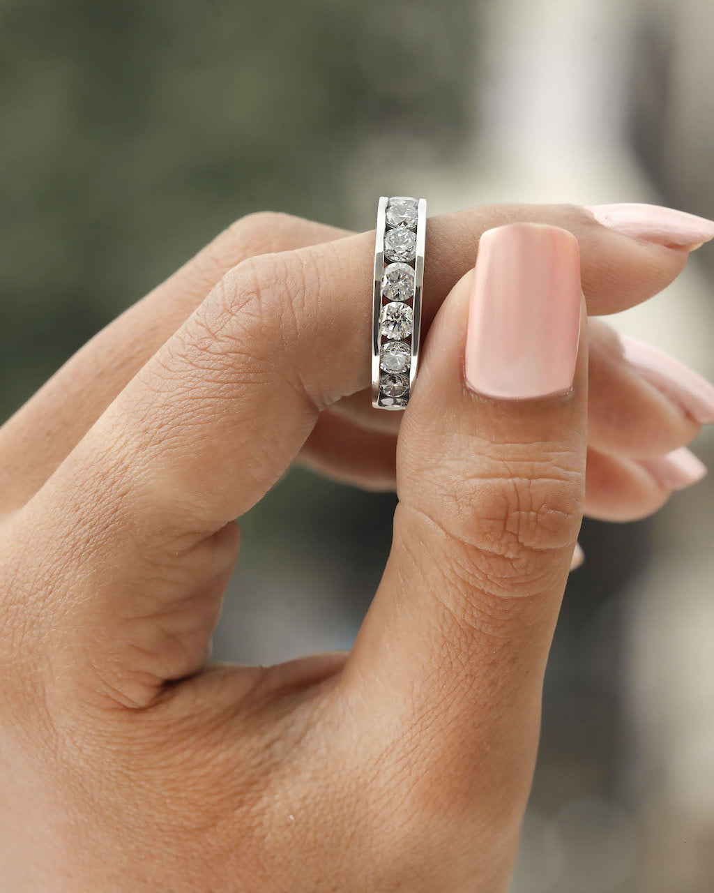 Hand holding channel set diamond eternity ring in white gold.