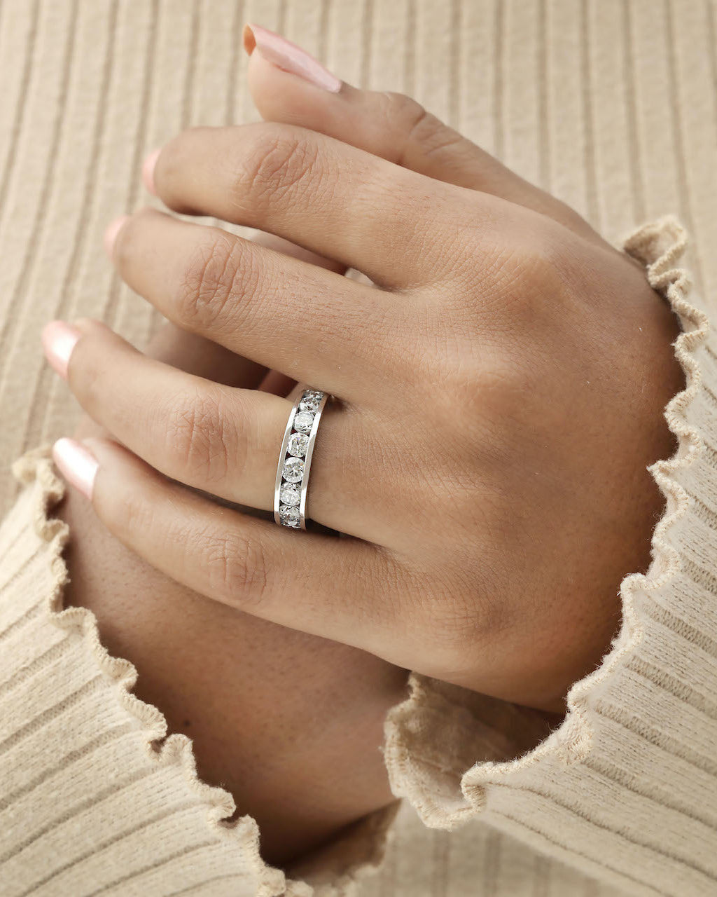 Hand wearing channel set diamond eternity ring in white gold.