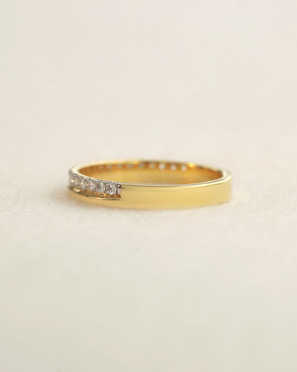 Yellow gold diamond band on a white background.