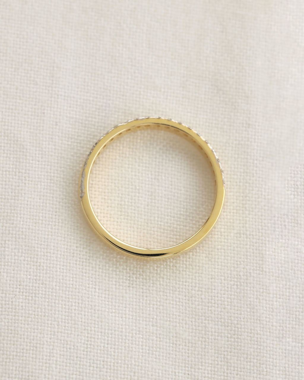 Yellow gold diamond band on a white background.