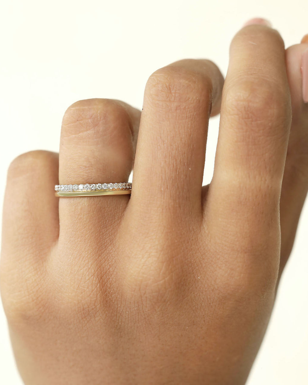Hand wearing a yellow gold diamond band.