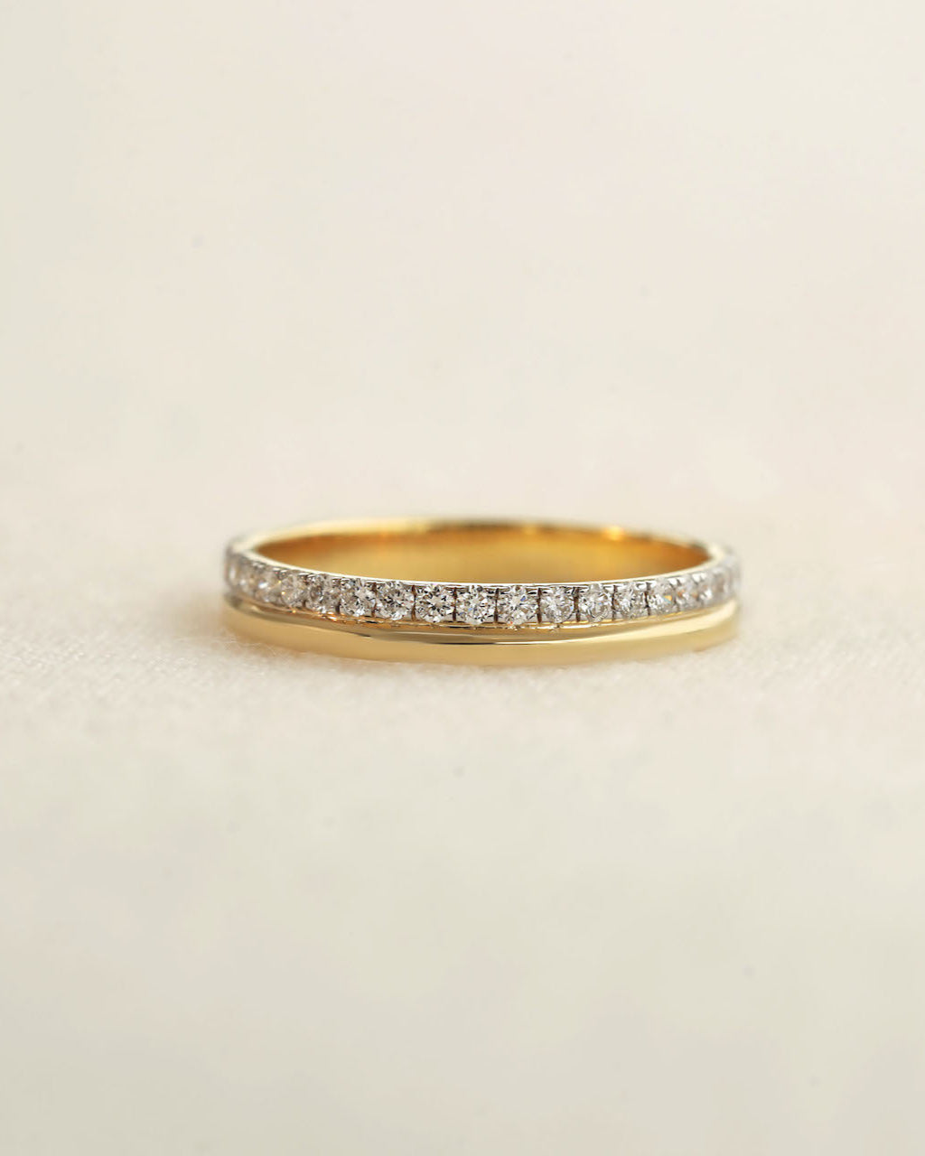 A yellow gold diamond band on a white background.
