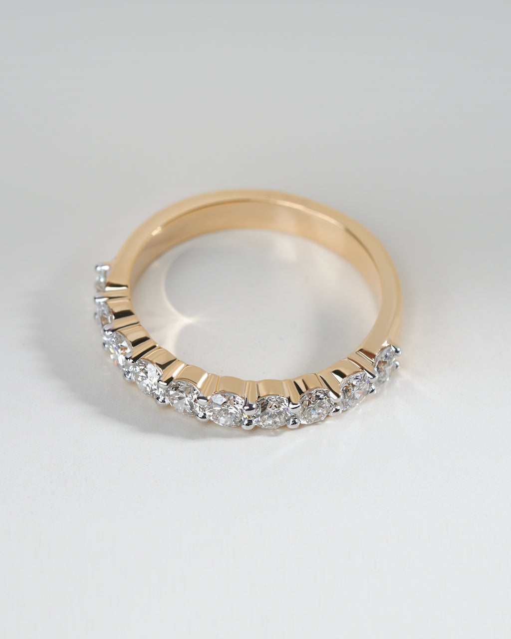 Gold ring with diamonds on a light gray background.