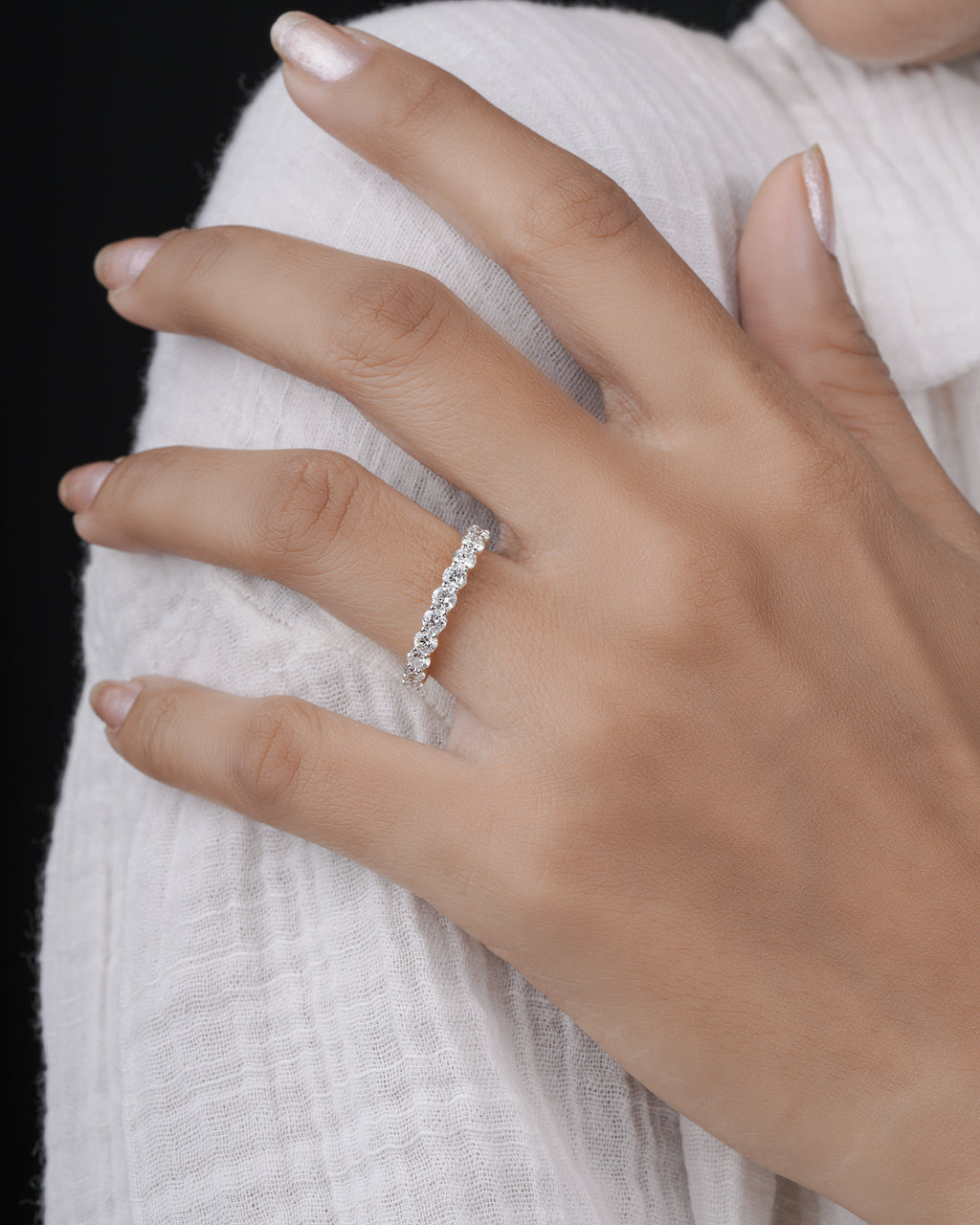 Close-up of a hand wearing a half eternity ring on a white background.