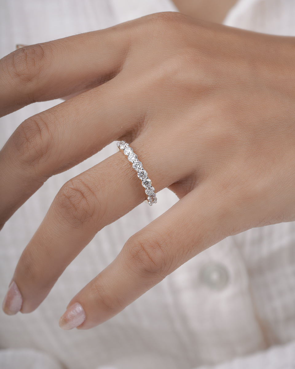 Close-up of a hand wearing a half eternity ring with a white background.