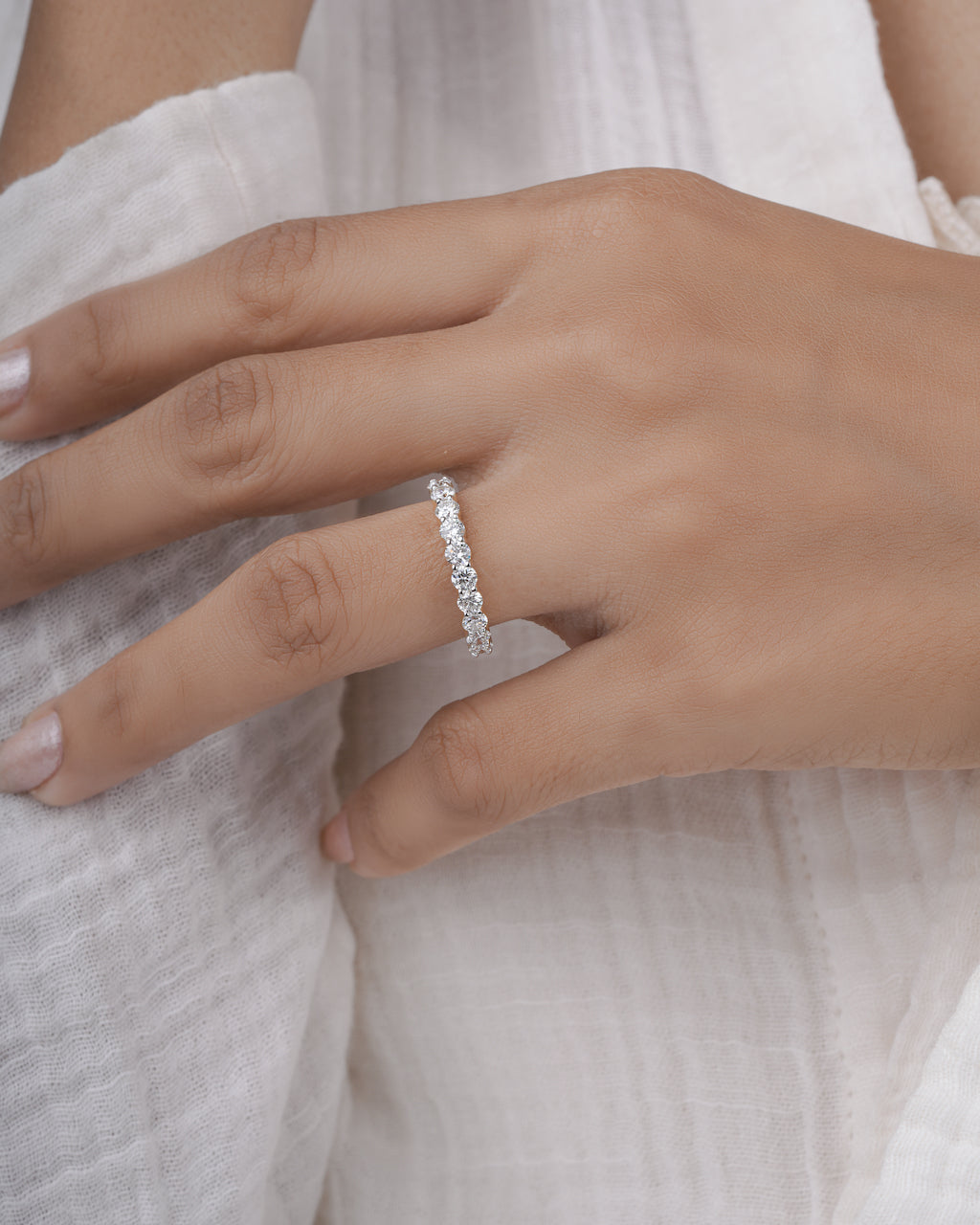 Close-up of a hand wearing a half eternity gold ring with a white background.