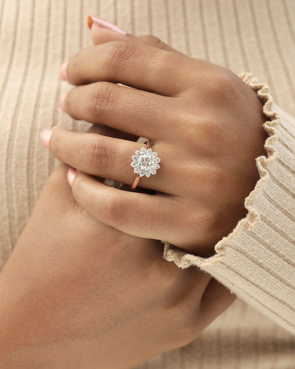 Hand wearing a diamond ring with a beige background.