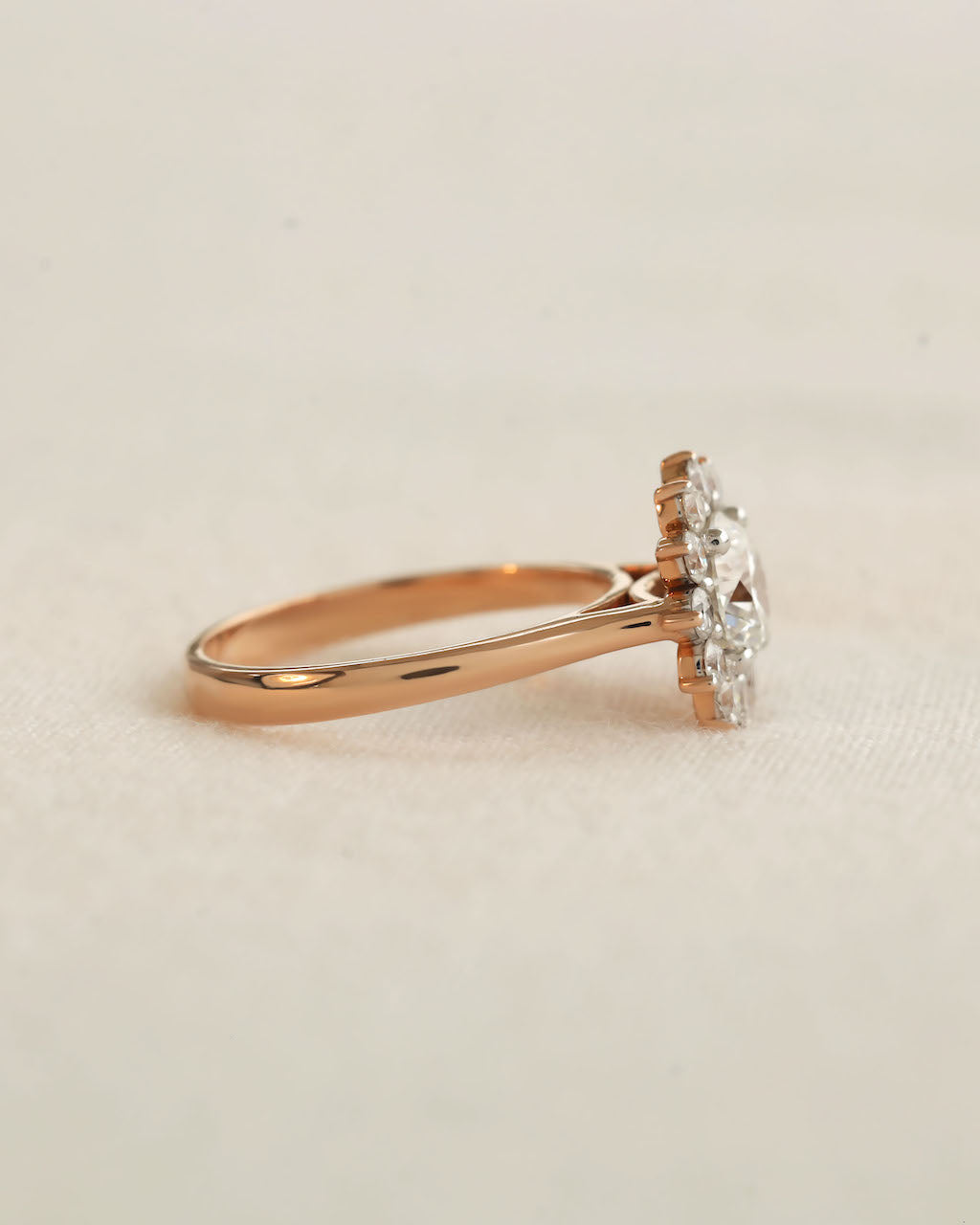 Rose gold ring with a diamond on a beige background.