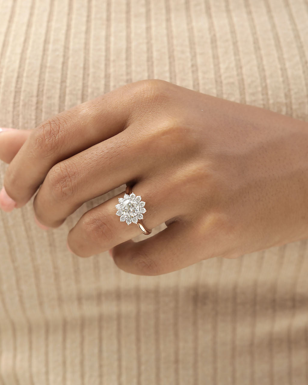 Hand wearing a diamond ring on a beige background.