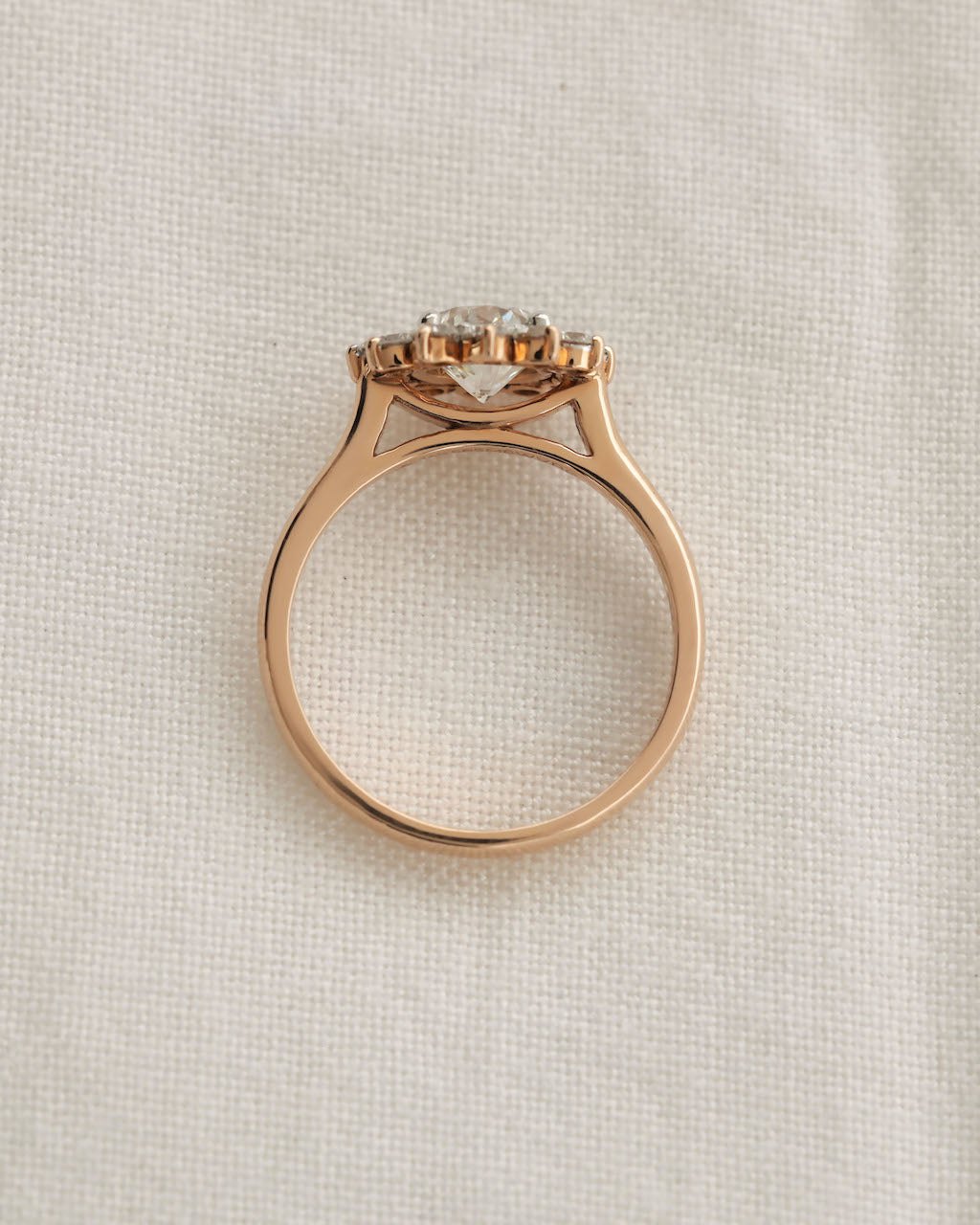 Rose gold ring with a diamond on a light beige textured background