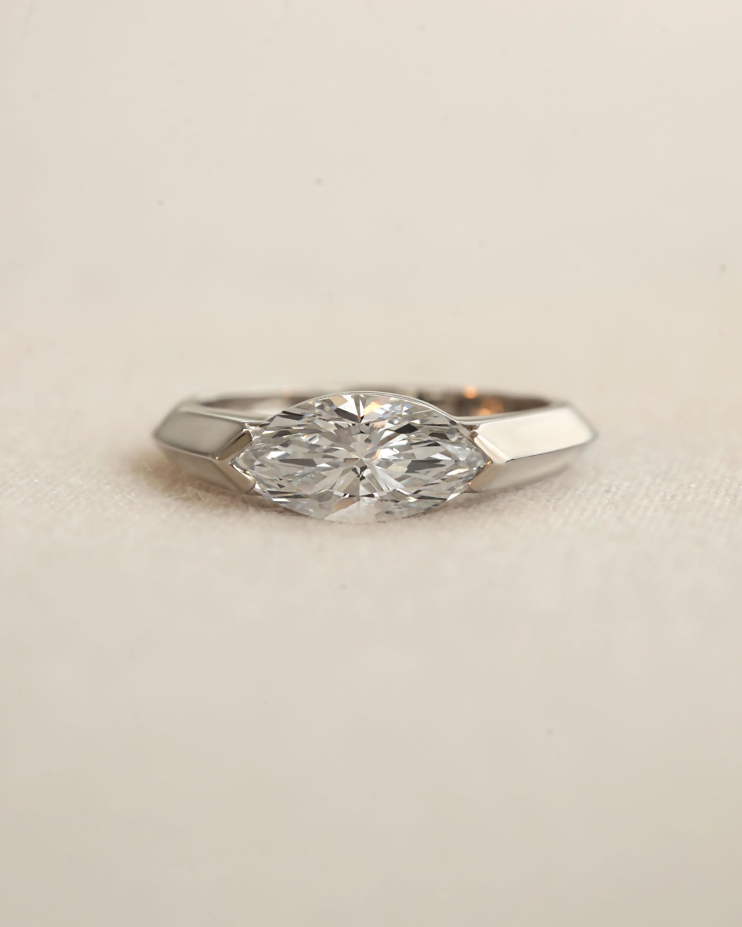 Marquise cut diamond bezel ring in white gold on white background.
