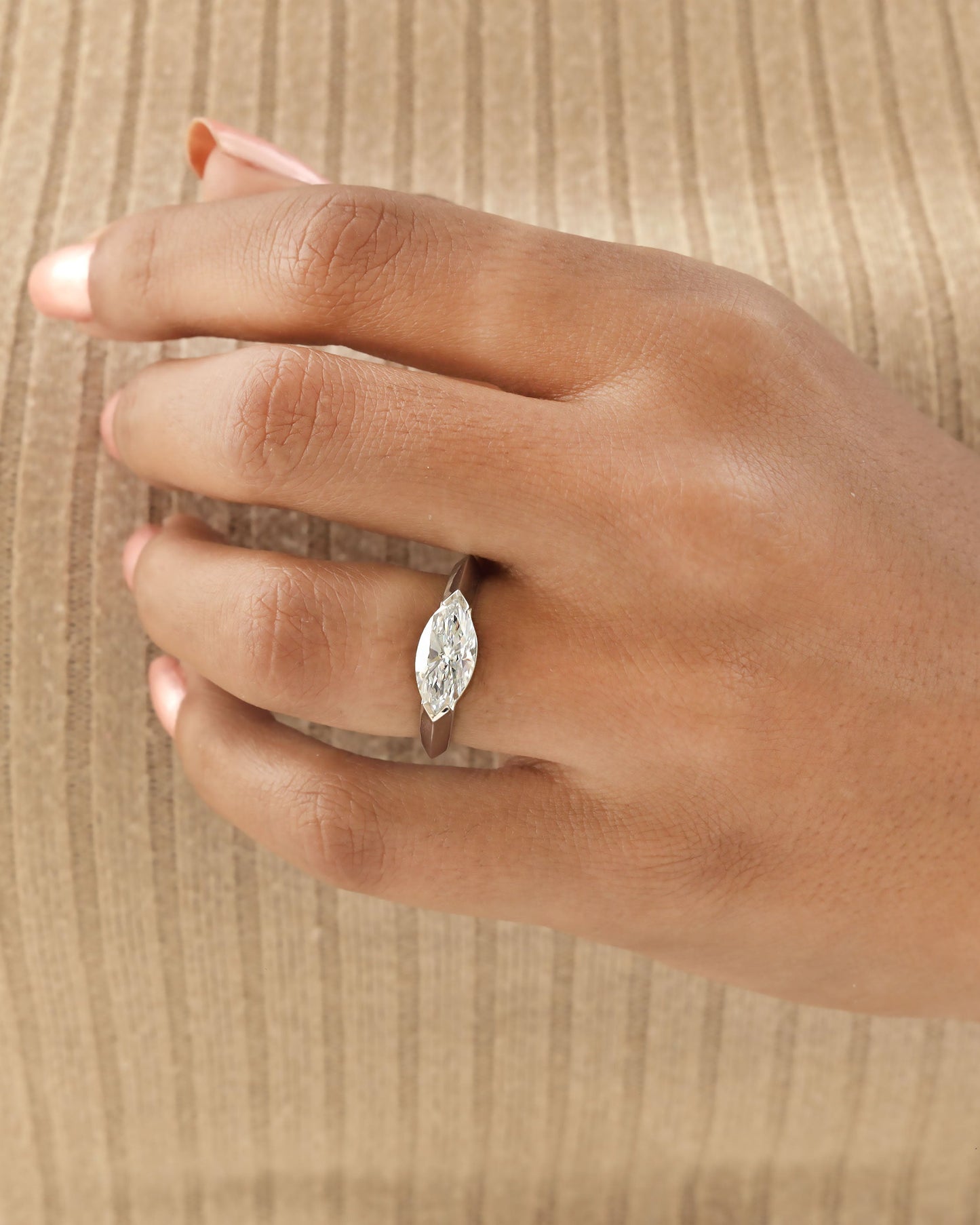 Hand wearing a marquise cut diamond bezel ring in white gold.