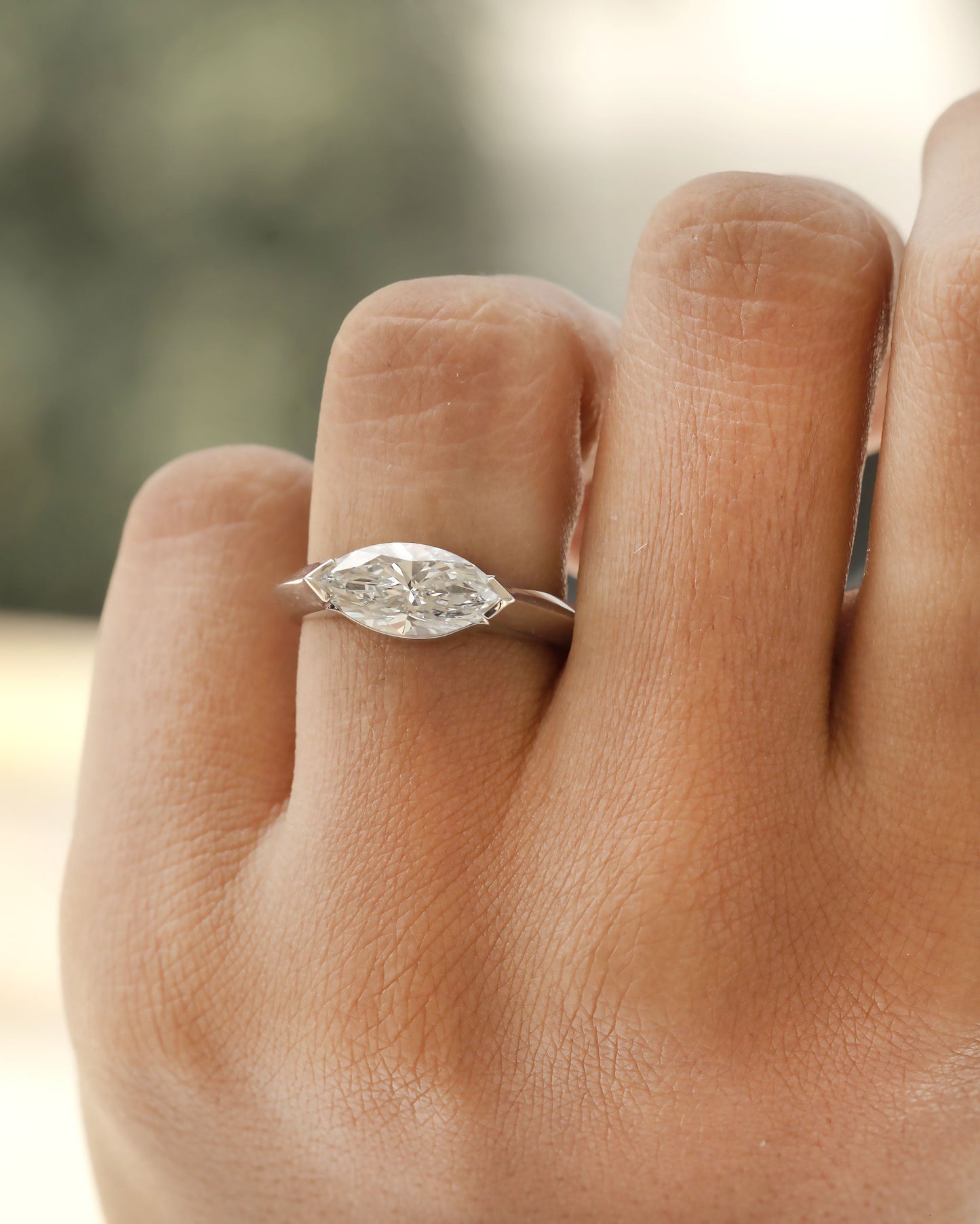 Hand wearing a marquise cut diamond bezel ring in white gold.
