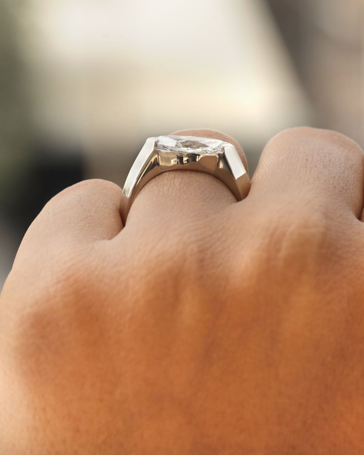 Hand wearing a marquise cut diamond bezel ring in white gold.
