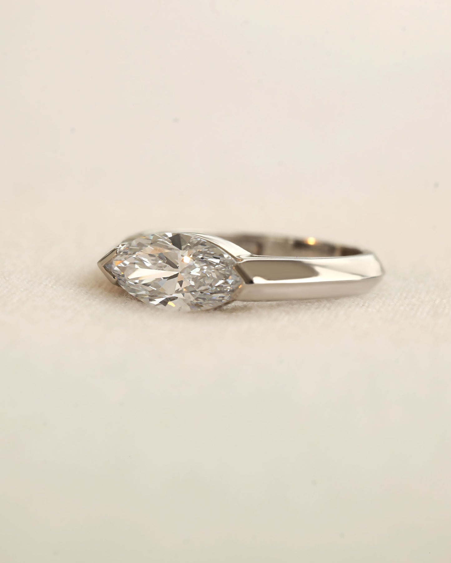 Marquise cut diamond bezel ring in white gold on white background.