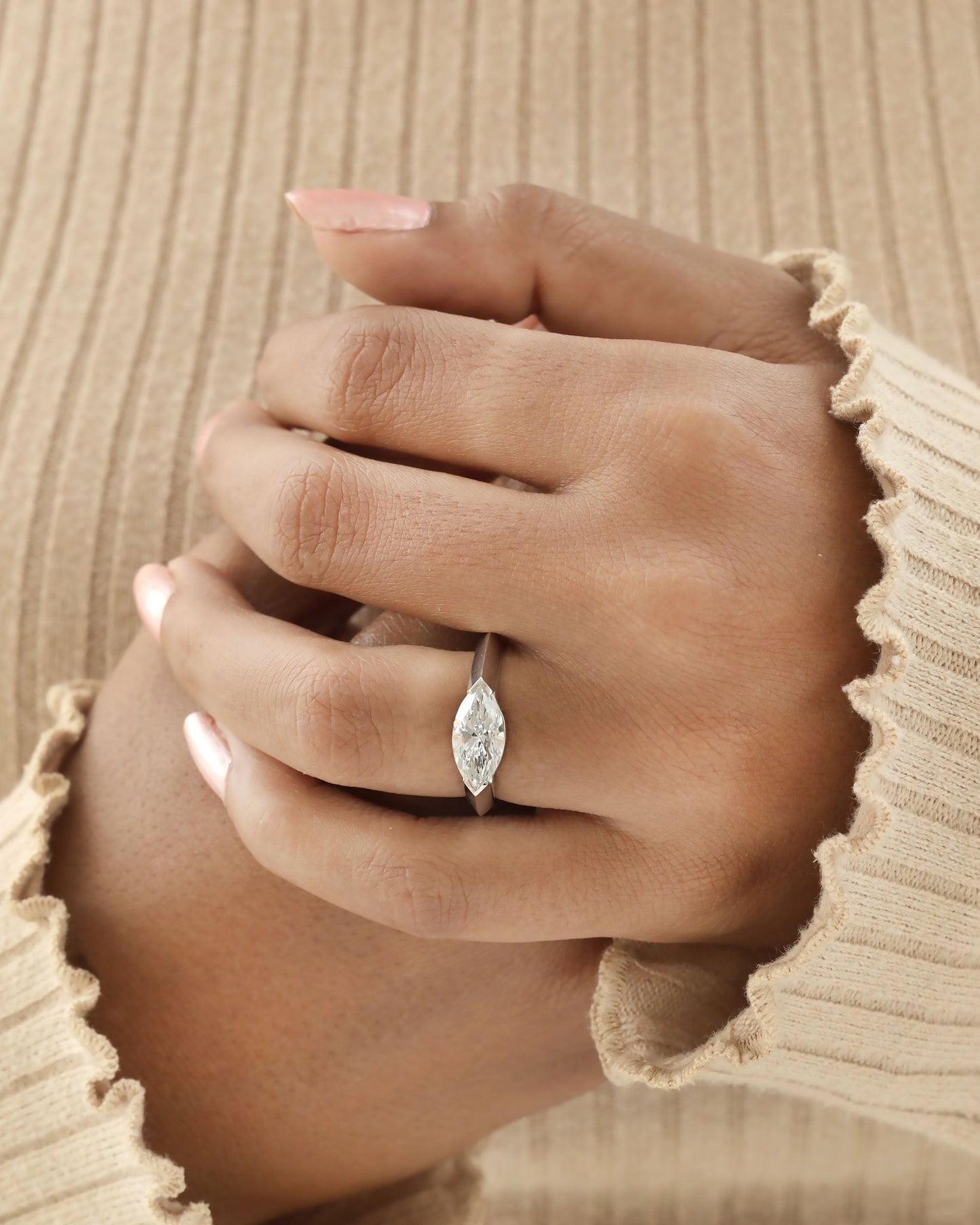 Hand wearing a marquise cut diamond bezel ring in white gold.