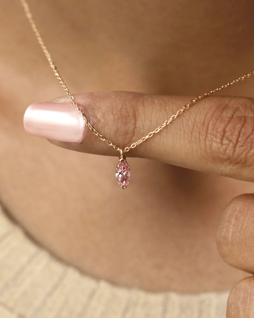 Person wearing marquise cut lab diamond solitaire pendant necklace in yellow gold.