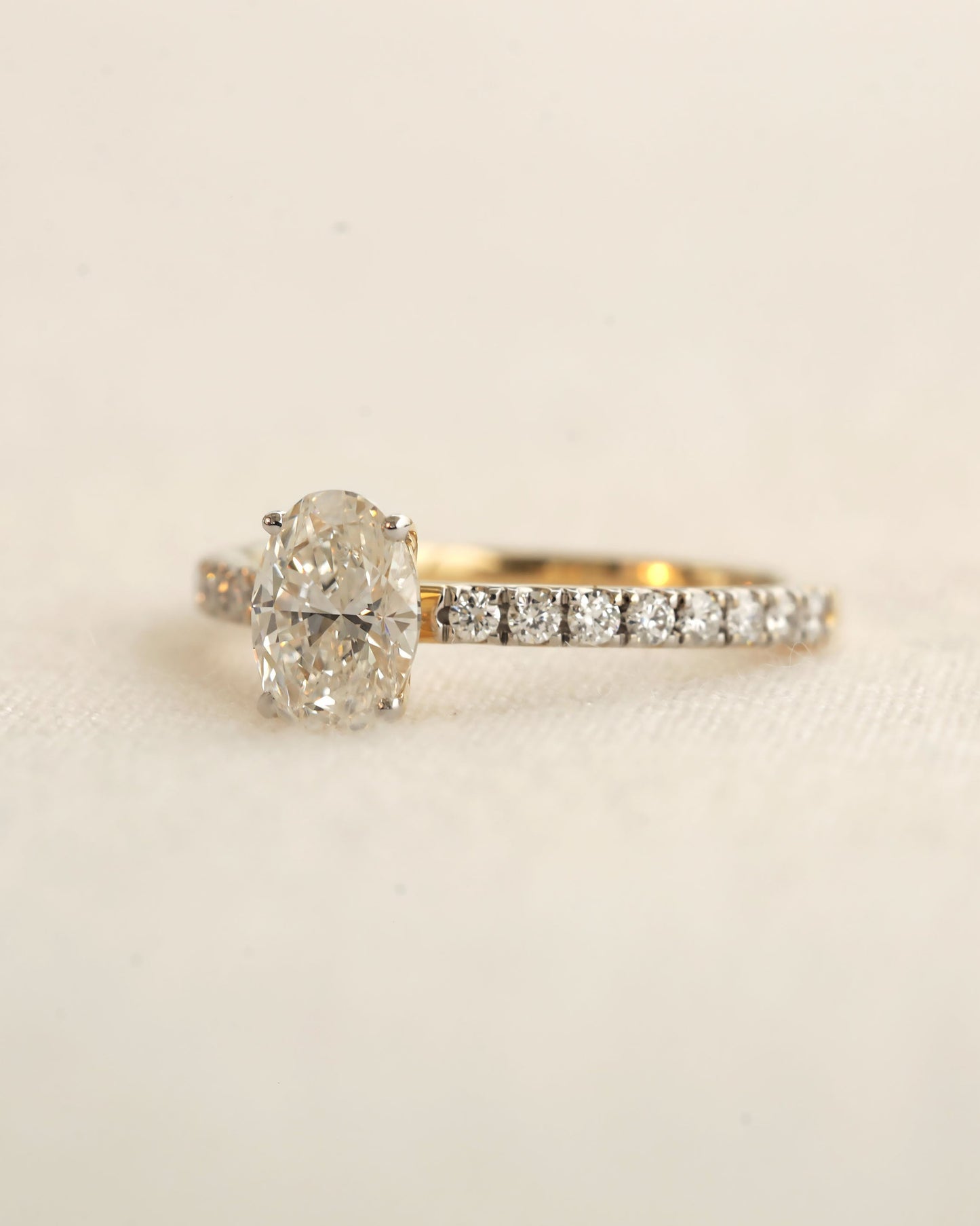 Close u shot of oval cut lab-grown diamond engagement ring in yellow gold.