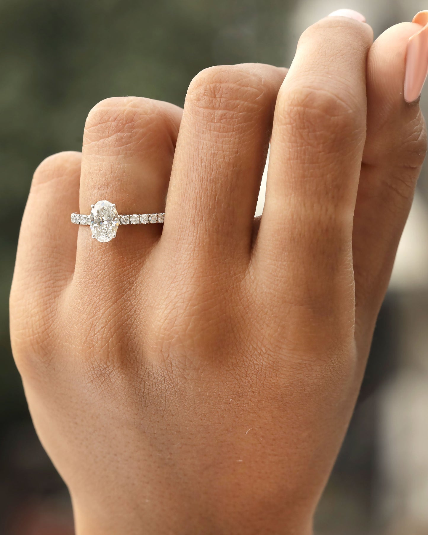 Hand wearing oval cut lab-grown diamond engagement ring in yellow gold.