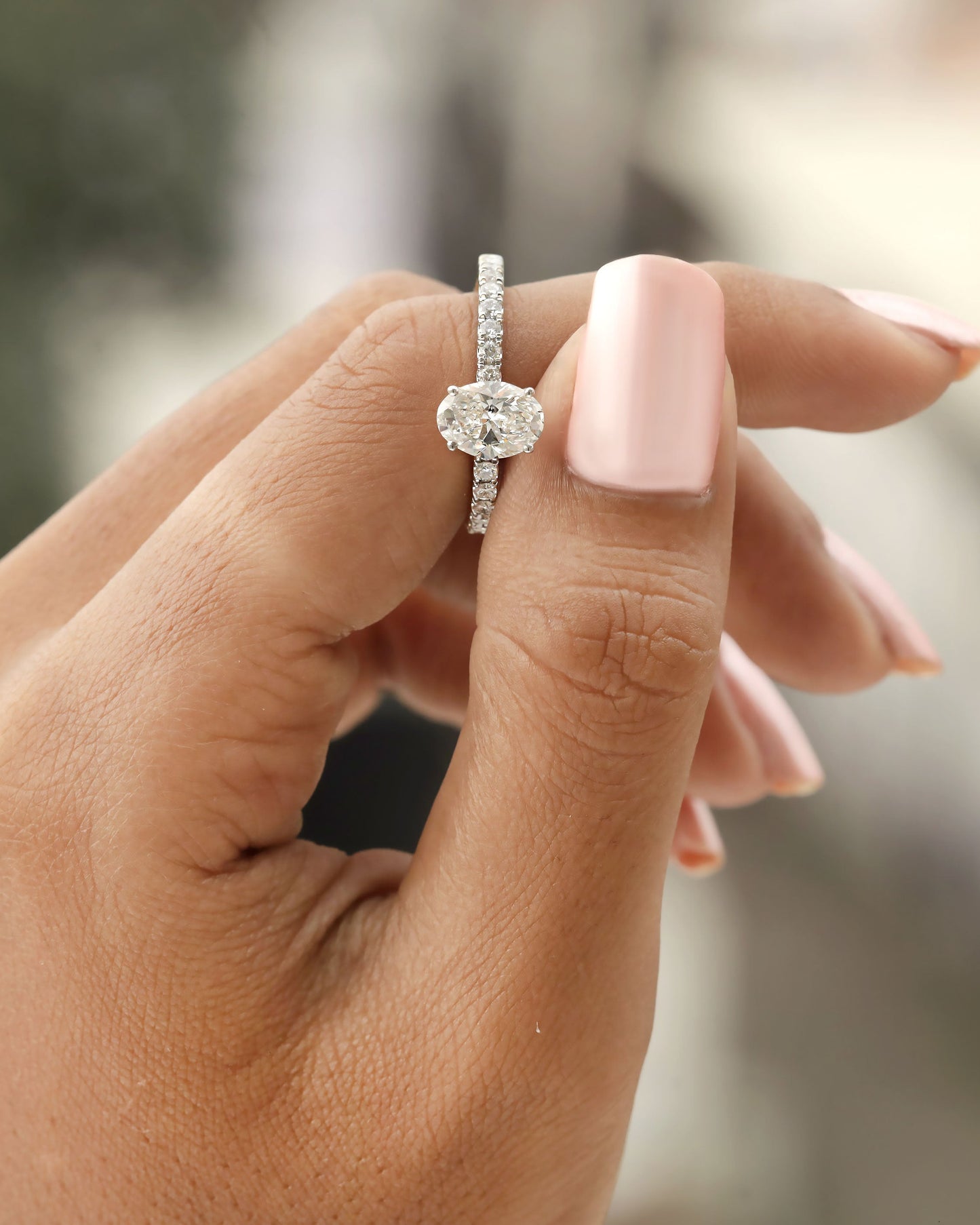 Hand holding oval cut lab-grown diamond engagement ring in yellow gold.