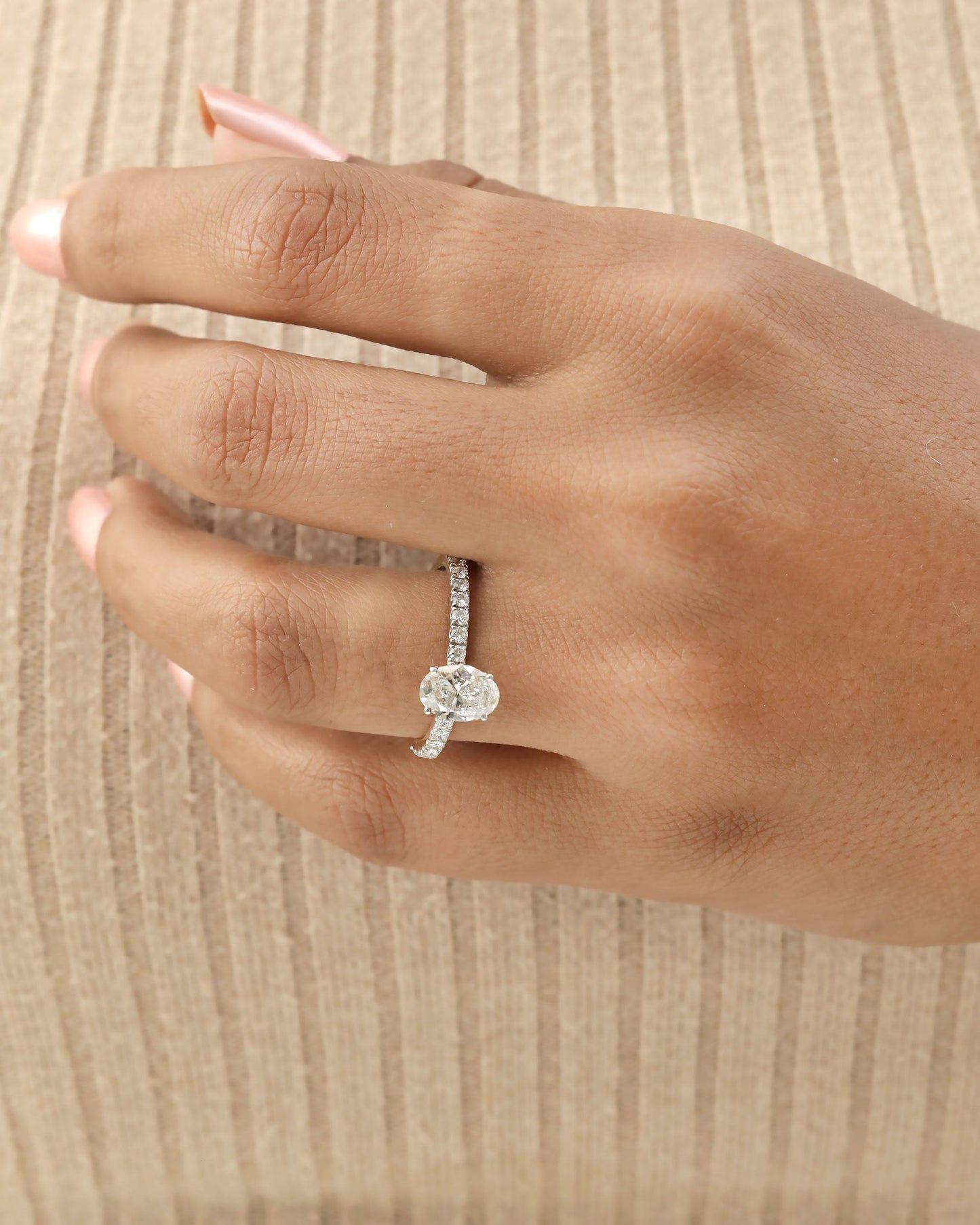 Hand wearing oval cut lab-grown diamond engagement ring in yellow gold.