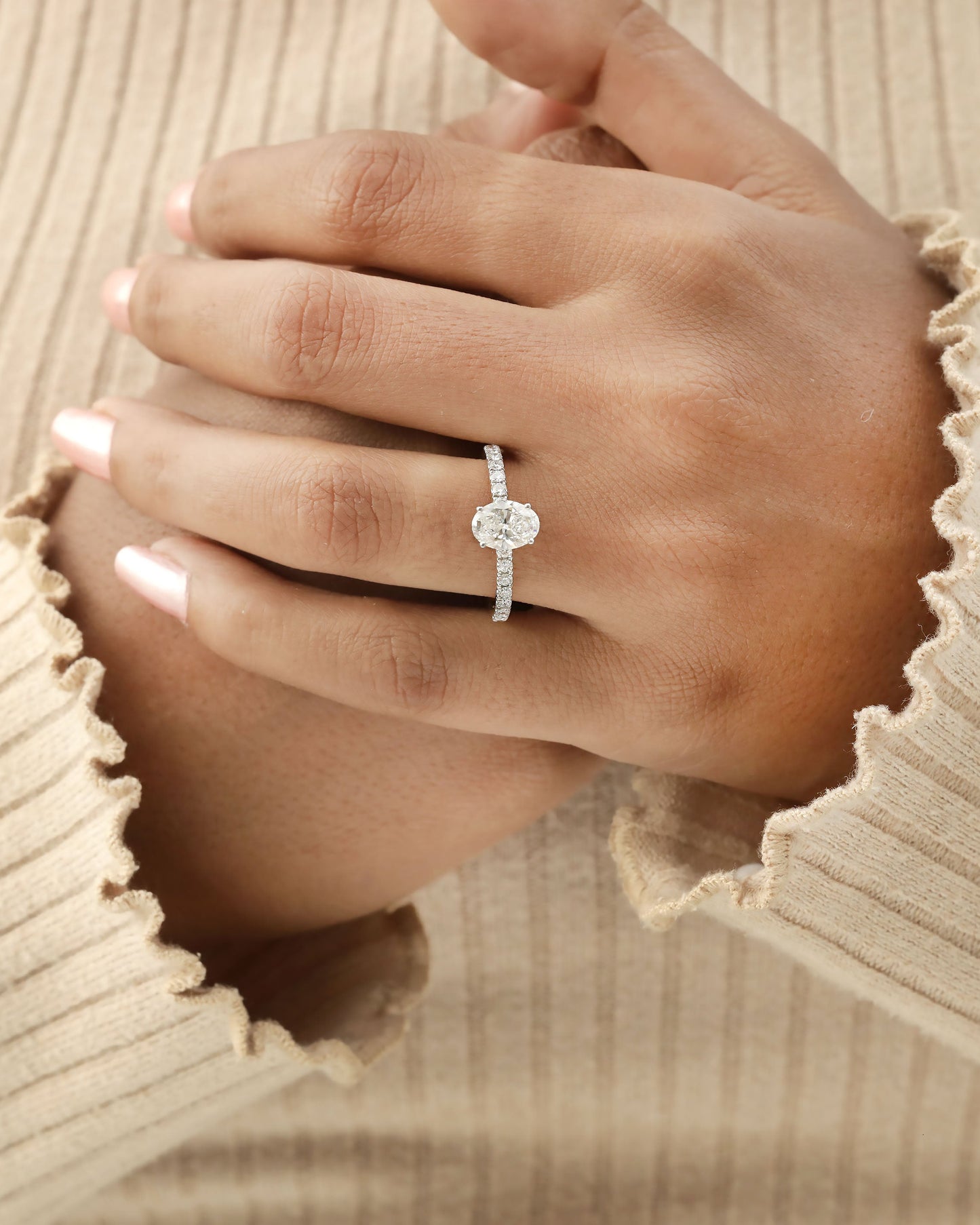Hand wearing oval cut lab-grown diamond engagement ring in yellow gold.