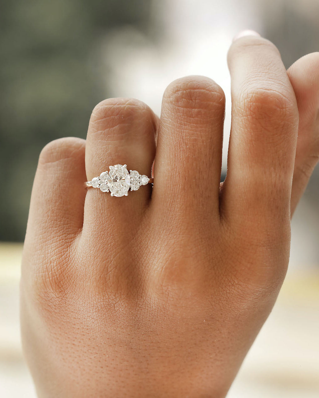 Hand wearing oval cut diamond engagement ring in rose gold.