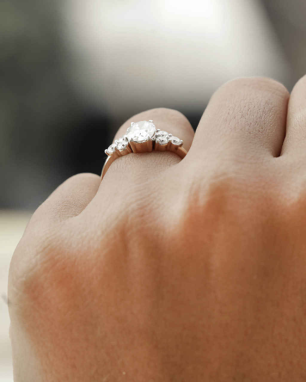 Hand wearing oval cut diamond engagement ring in rose gold.