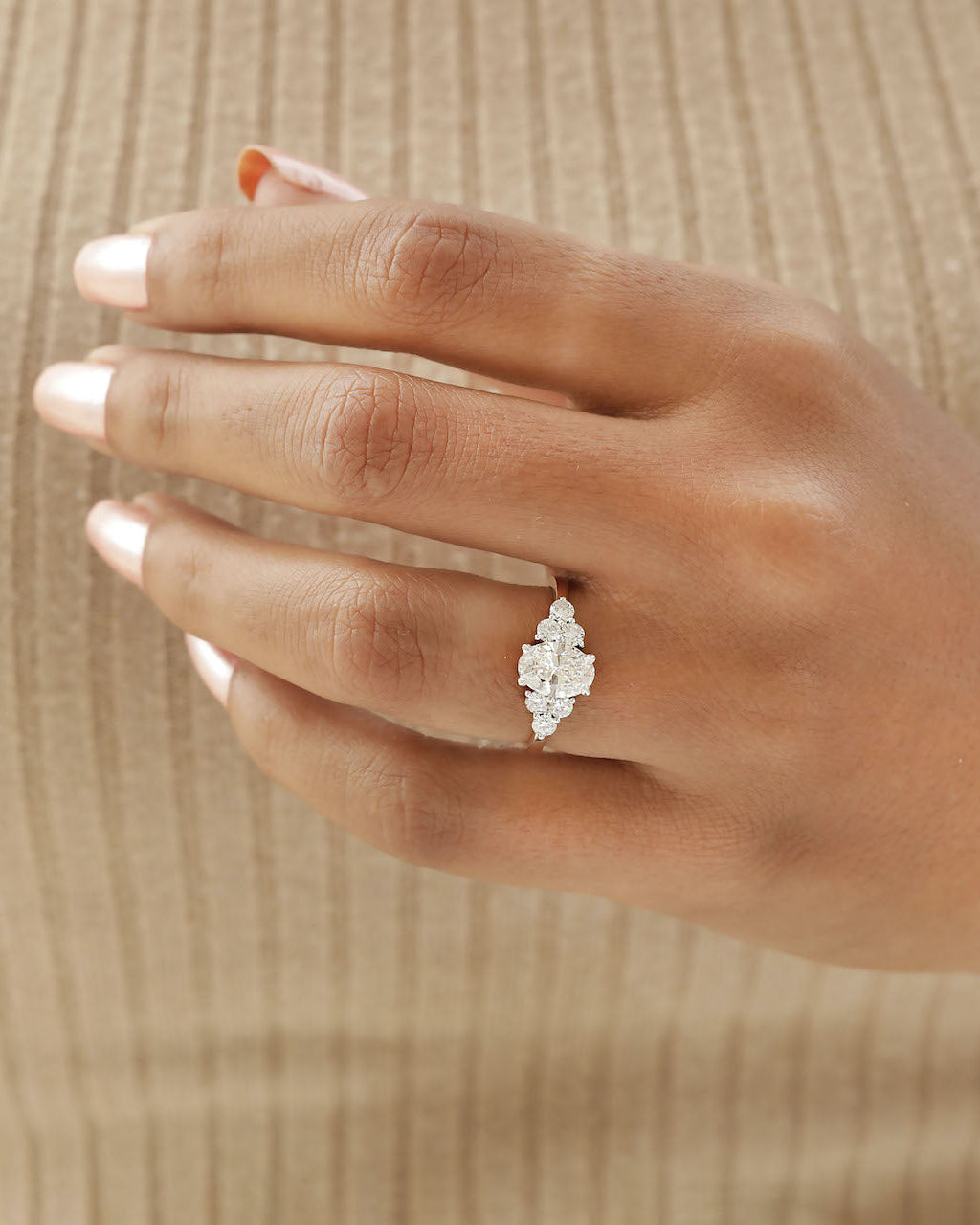 Hand wearing oval cut diamond engagement ring in rose gold.