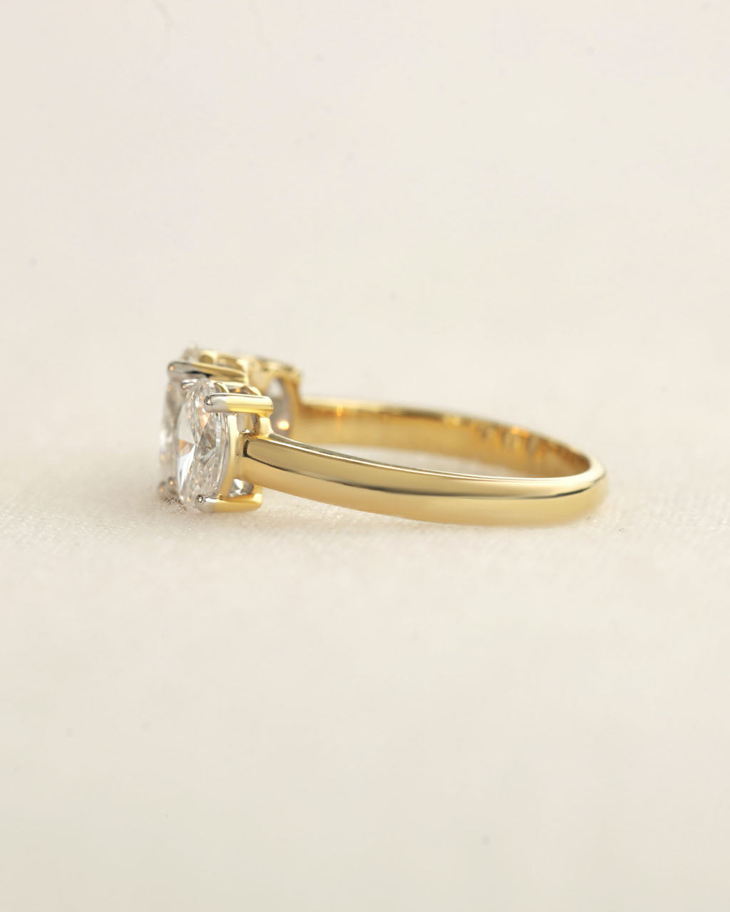 Side view of a oval cut three stone diamond ring.