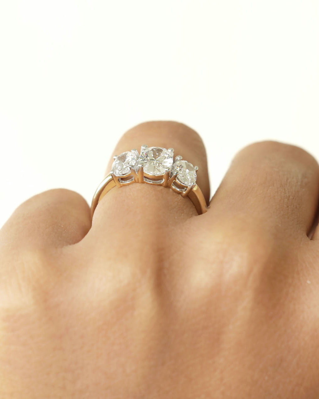 Hand wearing a three stone diamond yellow gold ring.