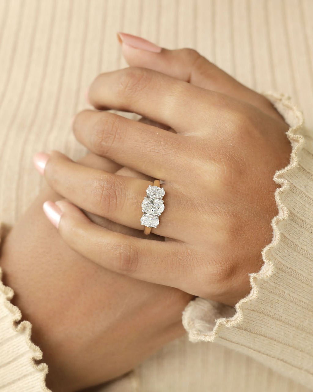 Hand wearing a oval cut three stone diamond ring.