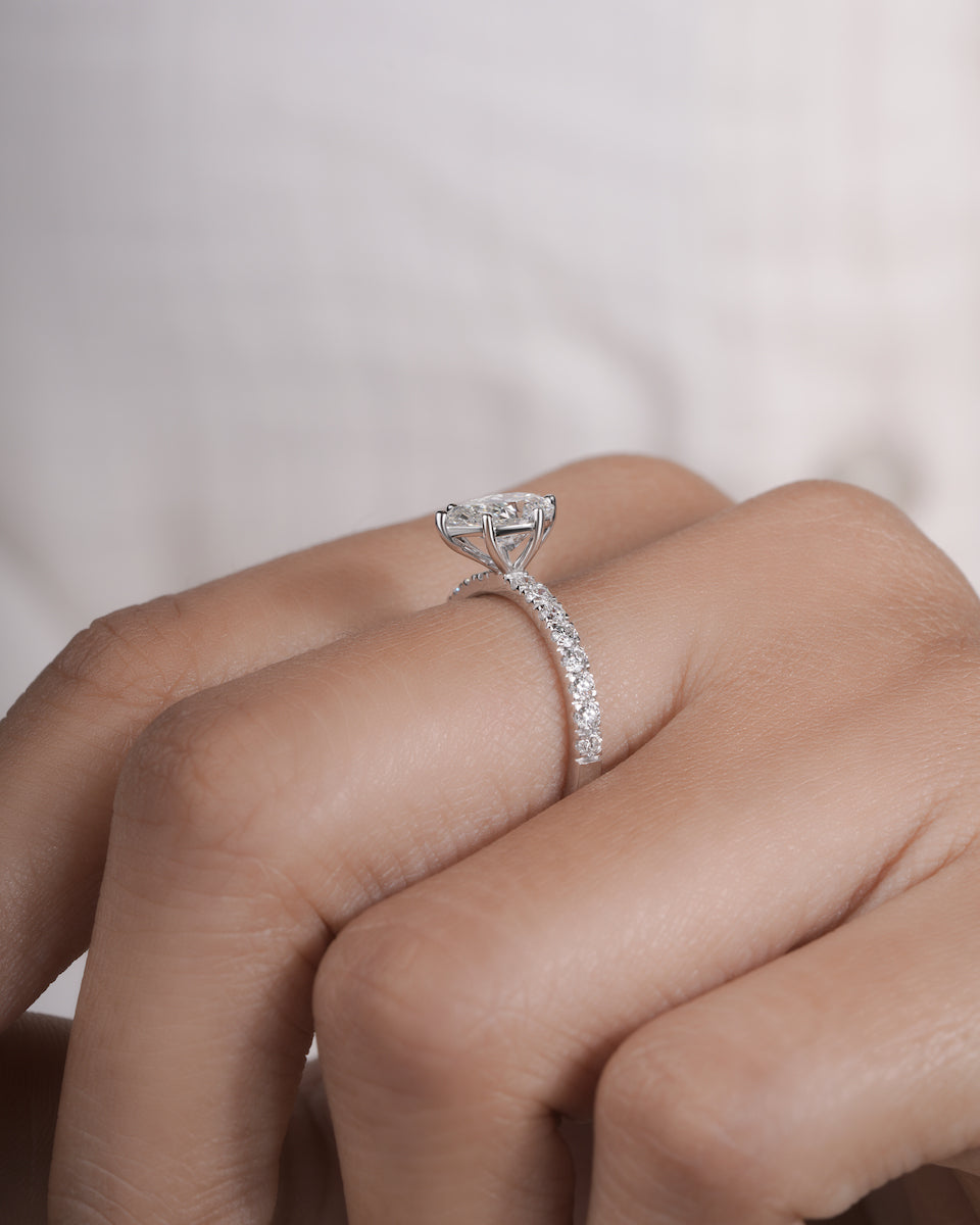 Hand wearing pear cut lab grown diamond engagement ring in white gold.