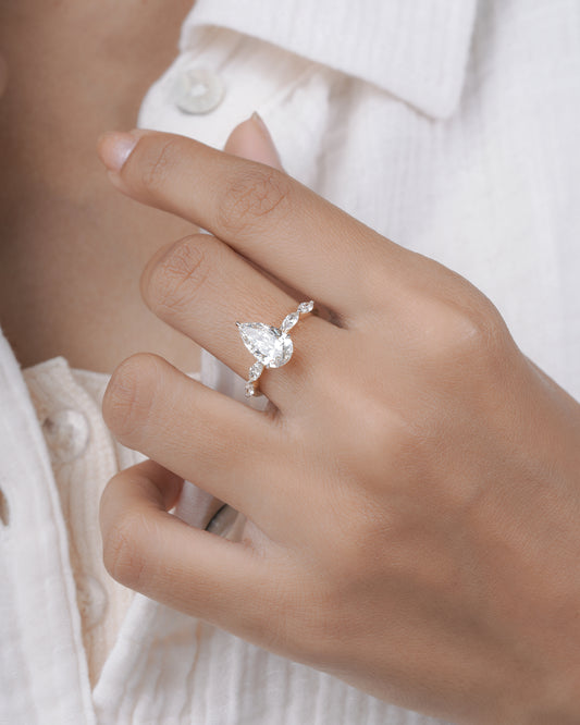 Diamond ring with pear-shaped center stone on a hand.