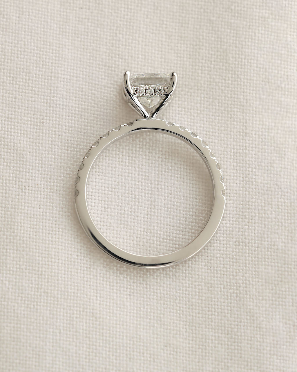 Close up shot of princess cut diamond ring displayed on a white background.