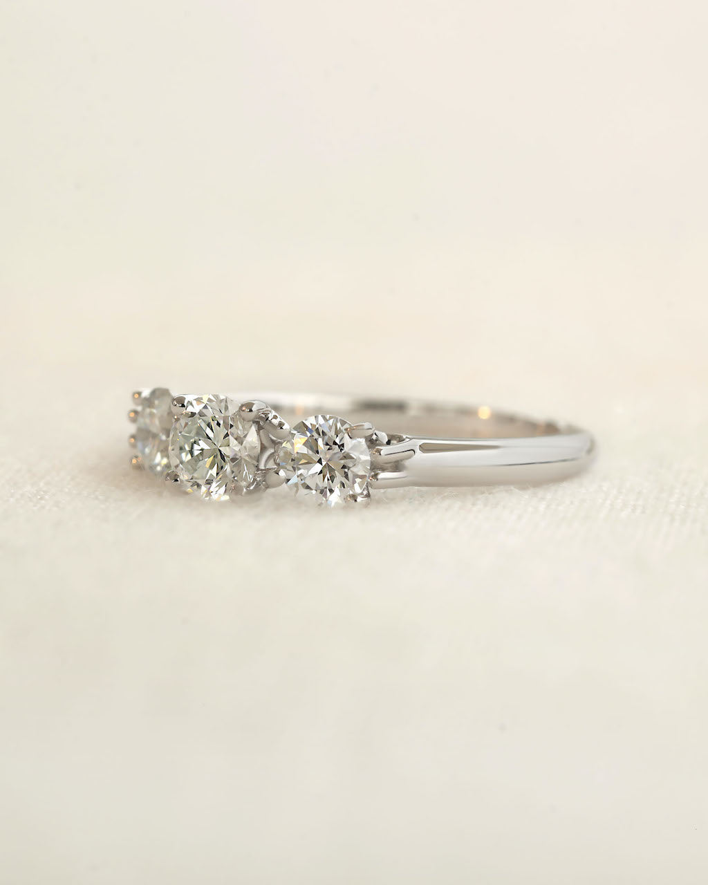 Three stone round cut lab grown diamond ring on a white background.