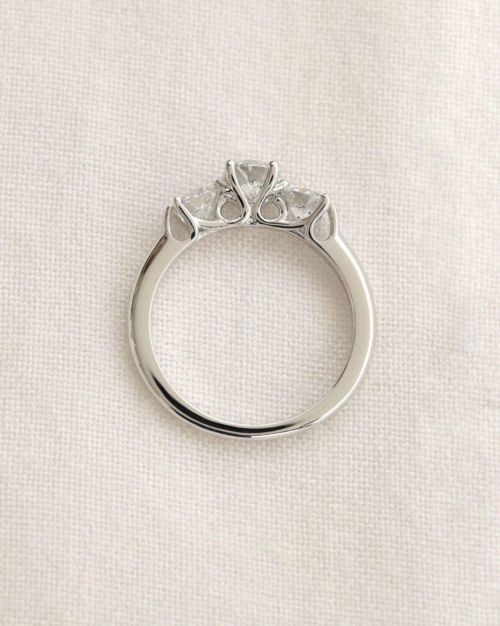 Three stone round cut diamond ring on a white background.