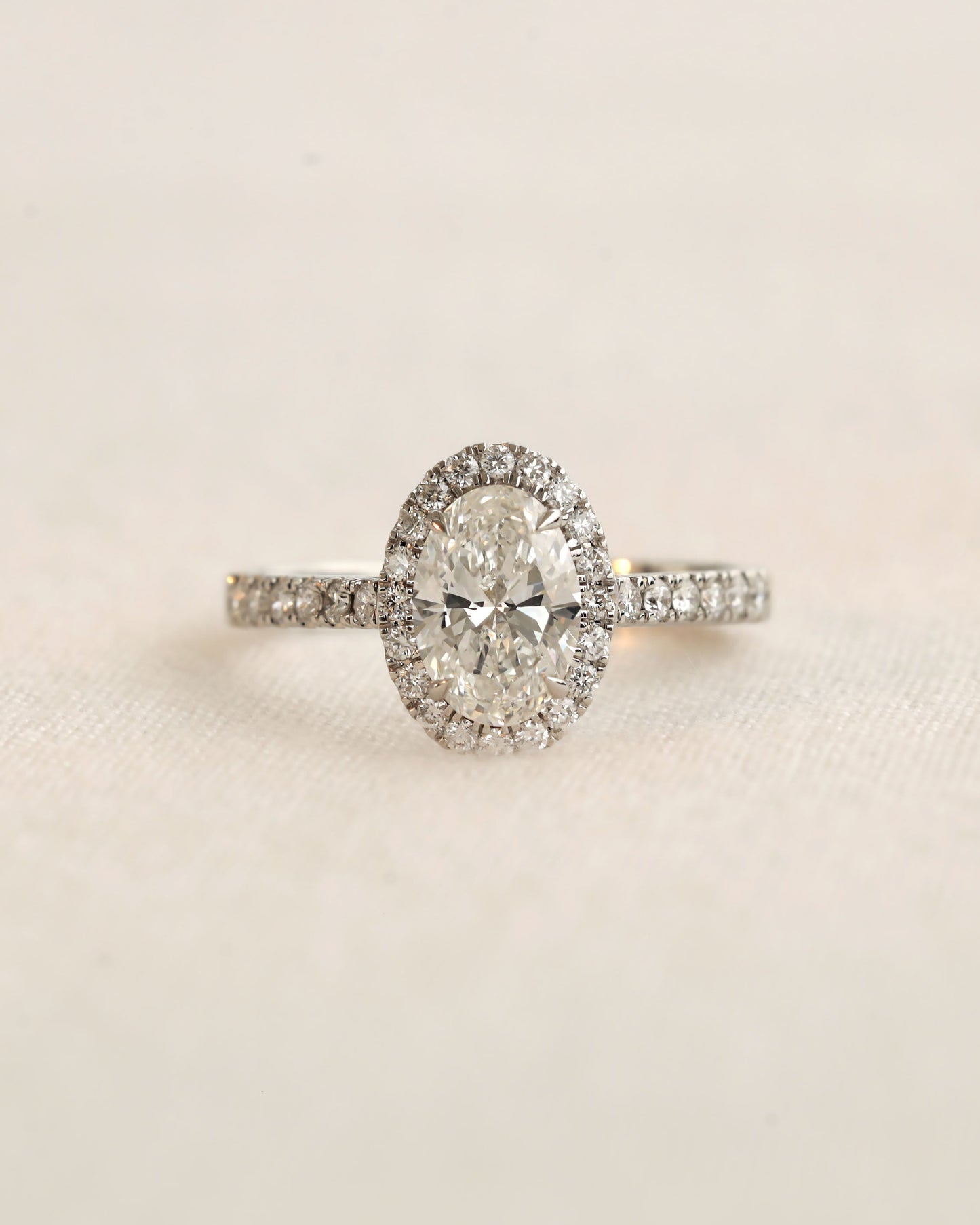 Close up shot of white gold oval halo engagement ring.