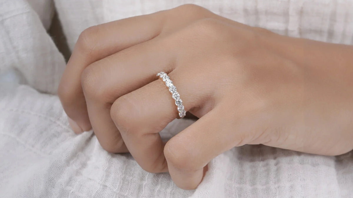 Hand wearing a lab diamond wedding ring on a light fabric background