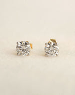 Pair of diamond stud earrings on a light beige background