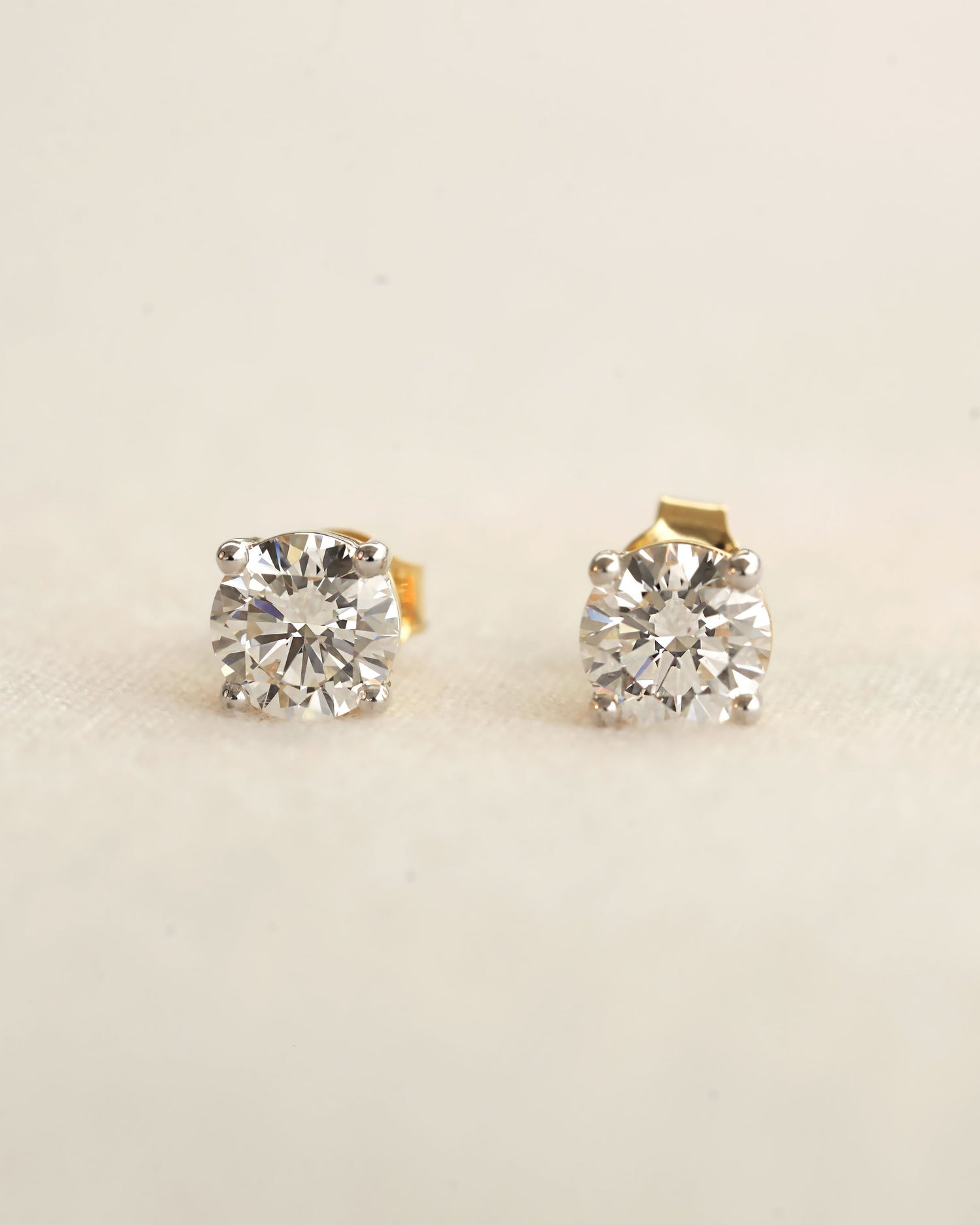 Pair of diamond stud earrings on a light beige background